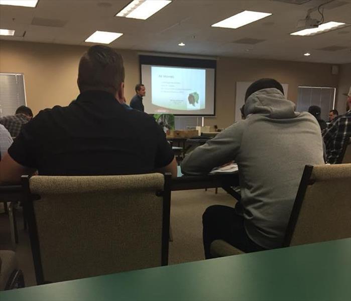 SERVPRO training center room with projector screen and rows of tables and chairs