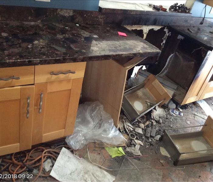 kitchen shows fire damage to cabinets and flooring from stove fire